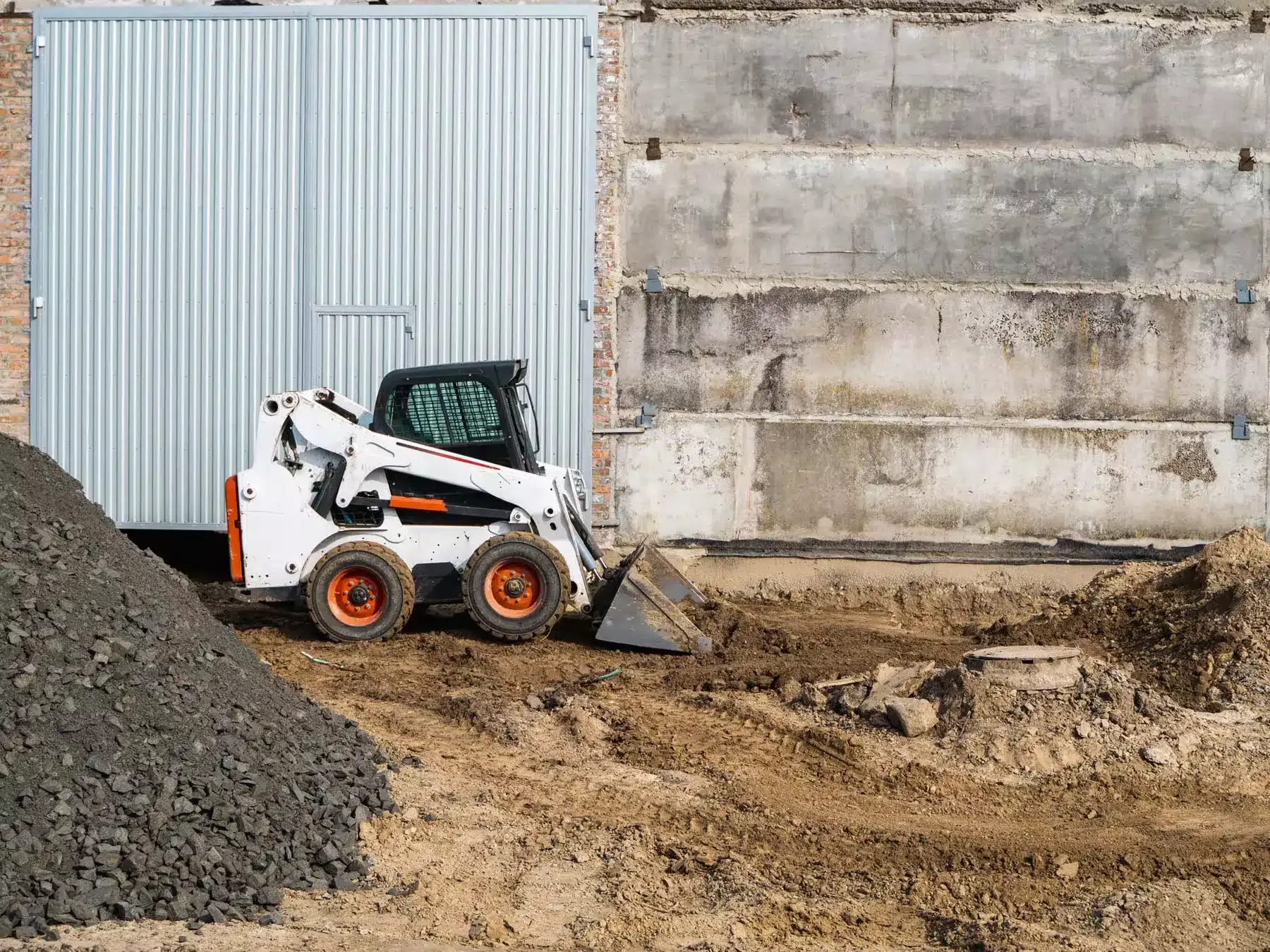 Bobcat skid-steer loader grading dirt at a construction site