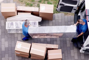 Crew unloading wrapped furniture and boxes from a van