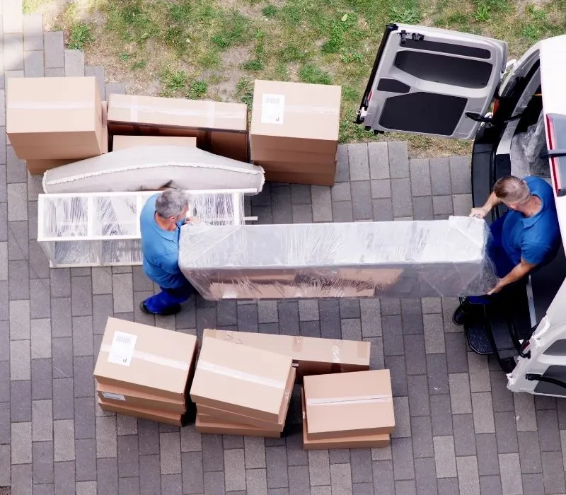 Movers loading wrapped furniture and boxes into a van