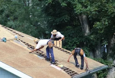 Roofers laying new shingles on a house roof