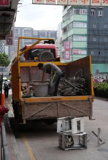 Worker clearing scrap and debris from the bed of a pickup truck