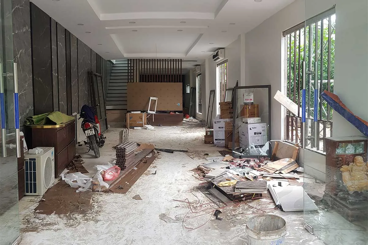 Before: a room littered with construction debris, boxes and a motorbike
